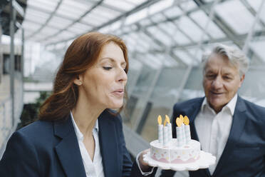 Geschäftsmann und Geschäftsfrau feiern Geburtstag im Büro mit gefälschter Geburtstagstorte - JOSF04216