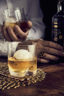Scotch with ice, mans hands in background - DREF00003