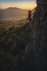 Mann klettert am Battert-Felsen bei Sonnenuntergang, Baden-Baden, Deutschland - MSUF00124