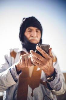 Senior man using cell phone in Smara refugee camp, Tindouf, Algeria - OCMF00957