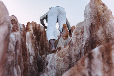 Rückansicht eines jungen Mannes, der auf Felsen klettert - ERRF02429