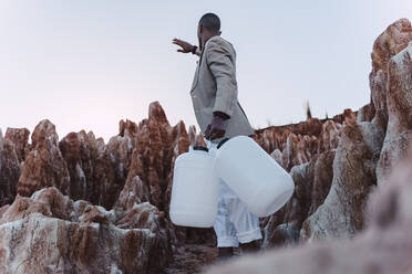 Junger Mann mit leerem Kanister auf der Suche nach Wasser im kargen Land - ERRF02430
