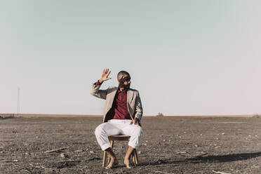 Young man sitting on chair in barren land - ERRF02442