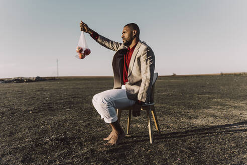 Young man sitting on chair in barren land - ERRF02467