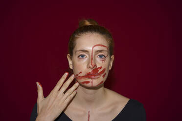 Porträt einer jungen Frau, die Farbe auf ihr Gesicht schmiert - AFVF04804