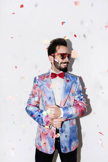 Cool and stylish man wearing a colorful suit and sunglasses smiling at a party surrounded by confetti - LOTF00088