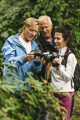 Ein älterer Mann zeigt einer Ausbilderin und einem Freund während eines Fotokurses die Kamera - MASF15995