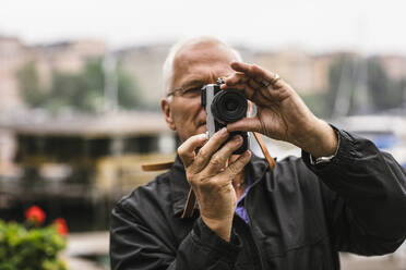 Senior man using camera during photography course - MASF15997