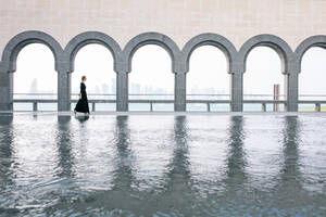Junge Frau beim Spaziergang am Pool im Museum für islamische Kunst in Doha - CAVF72572