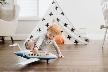 Kleinkind spielt mit Spielzeugflugzeug im Wohnzimmer - ISF23497