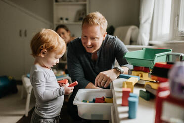 Vater beobachtet Sohn beim Spielen mit Bauklötzen im Wohnzimmer - ISF23501