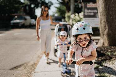 Mutter und Töchter spielen mit dem Roller in der Nachbarschaft - ISF23509