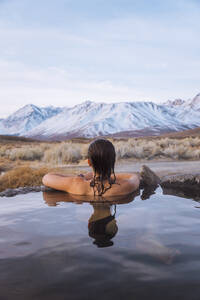 Woman enjoying hot spring in cold winter, Mammoth Lakes Hot Spring, California, USA - ISF23534