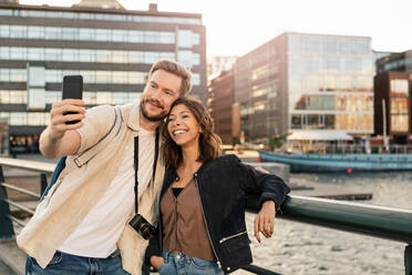 Man taking selfie with girlfriend on smart phone while exploring city - MASF16021