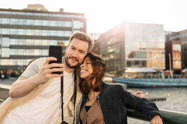 Verliebtes Paar beim Fotografieren mit dem Smartphone in der Stadt - MASF16022