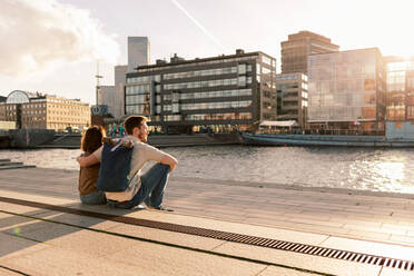 Couple sitting on promenade while looking at river in city - MASF16025