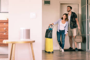 Paar in voller Länge mit Gepäck, das sich in der Wohnung umsieht, während es an der Tür steht - MASF16028