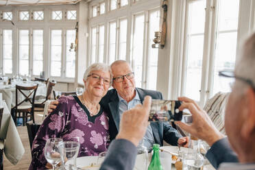 Männlicher Freund, der das Foto eines älteren Paares im Restaurant anklickt - MASF16036