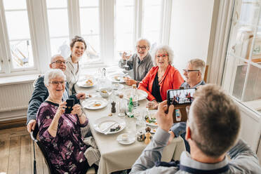 Kellner, der ein Foto von älteren Freunden im Restaurant anklickt - MASF16039