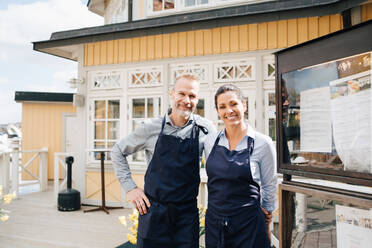 Portrait of smiling owners outside of restaurant - MASF16050