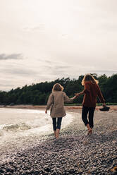 Rückansicht eines Paares, das gemeinsam am Strand spazieren geht, gegen den Himmel - MASF16081