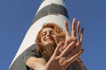 Portrait of happy redheaded young woman at a lighthouse - AFVF04851