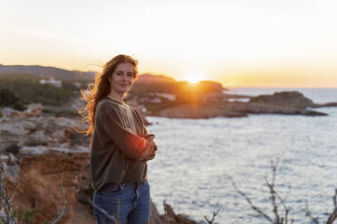 Porträt einer rothaarigen jungen Frau an der Küste bei Sonnenuntergang, Ibiza, Spanien - AFVF04870