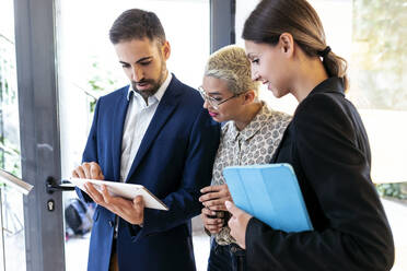 Businessman showing tablet to colleagues in office - JSRF00738