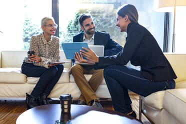 Smiling colleagues working together in lounge - JSRF00741