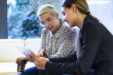 Two businesswomen working together in lounge sharing tablet - JSRF00759