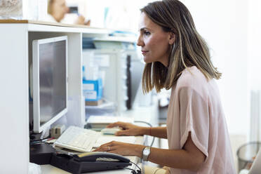Frau arbeitet am Computer an der Rezeption - JSRF00775