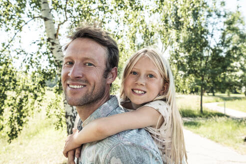 Portrait of happy father carrying daughter piggyback - WFF00222