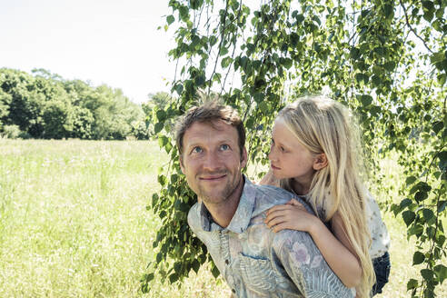 Father carrying daughter piggyback under a birch tree - WFF00224