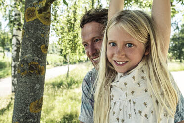 Portrait of a smiling girl with father hanging on a branch of a birch tree - WFF00230
