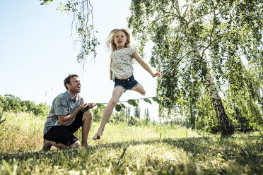 Vater mit Tochter springt über Stock in Mohnwiese - WFF00245