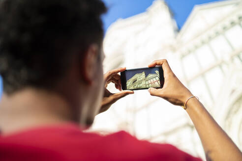 Junger Mann fotografiert mit seinem Smartphone die Basilica di Santa Maria del Fiore, Florenz, Italien - FBAF01140