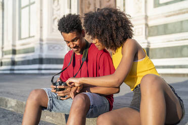 Glückliches junges Touristenpaar, das eine Pause in der Stadt macht und in die Kamera schaut, Florenz, Italien - FBAF01150