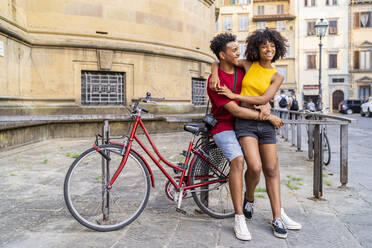 Glückliches junges Paar mit Fahrrad in der Stadt, Florenz, Italien - FBAF01153