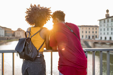 Junges Touristenpaar auf einer Brücke über dem Fluss Arno bei Sonnenuntergang, Florenz, Italien - FBAF01156