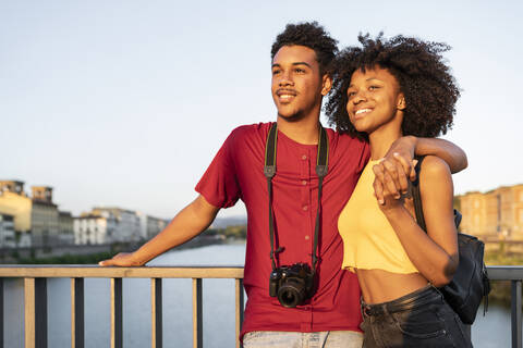 Glückliches junges Touristenpaar auf einer Brücke über den Fluss Arno bei Sonnenuntergang, Florenz, Italien, lizenzfreies Stockfoto