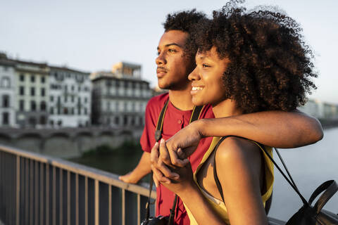 Glückliches junges Touristenpaar auf einer Brücke über den Fluss Arno bei Sonnenuntergang, Florenz, Italien, lizenzfreies Stockfoto