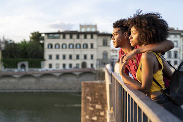 Junges Touristenpaar auf einer Brücke über den Fluss Arno bei Sonnenuntergang, Florenz, Italien - FBAF01165