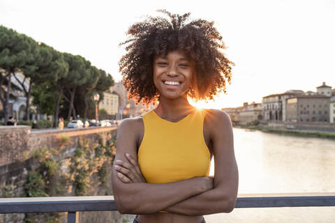 Porträt einer glücklichen jungen Frau auf einer Brücke über den Fluss Arno bei Sonnenuntergang, Florenz, Italien, lizenzfreies Stockfoto