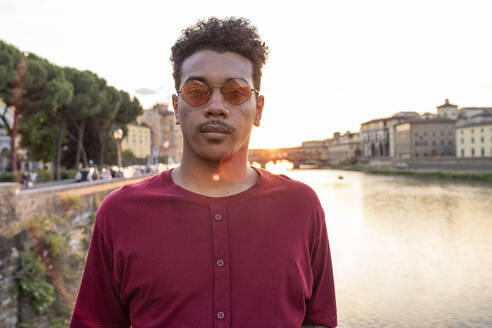Porträt eines jungen Mannes am Fluss Arno bei Sonnenuntergang, Florenz, Italien - FBAF01179