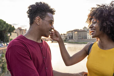 Happy young tourist couple at river Arno at sunset, Florence, Italy - FBAF01180