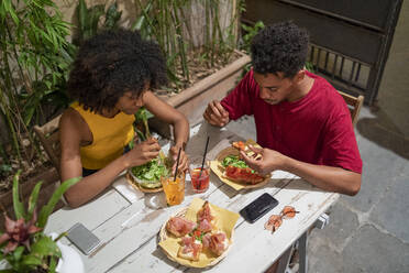 Young couple having a drink and amtipasti at an outdoor bar - FBAF01193