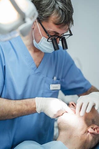 Zahnarzt bei der Arbeit an den Zähnen eines Patienten in einer Zahnarztpraxis, lizenzfreies Stockfoto