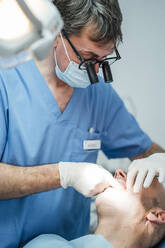 Dentist wotking on patient's teeth in dental surgery - OCMF00968