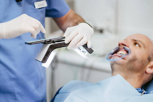 Nahaufnahme eines Zahnarztes, der eine Zahnprothese mit einem speziellen Fotoapparat fotografiert - OCMF00973