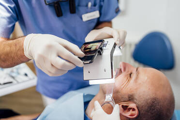 Nahaufnahme eines Zahnarztes, der eine Zahnprothese mit einem speziellen Fotoapparat fotografiert - OCMF00975